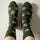 Dark green crew socks with a repeating sprout face pattern.